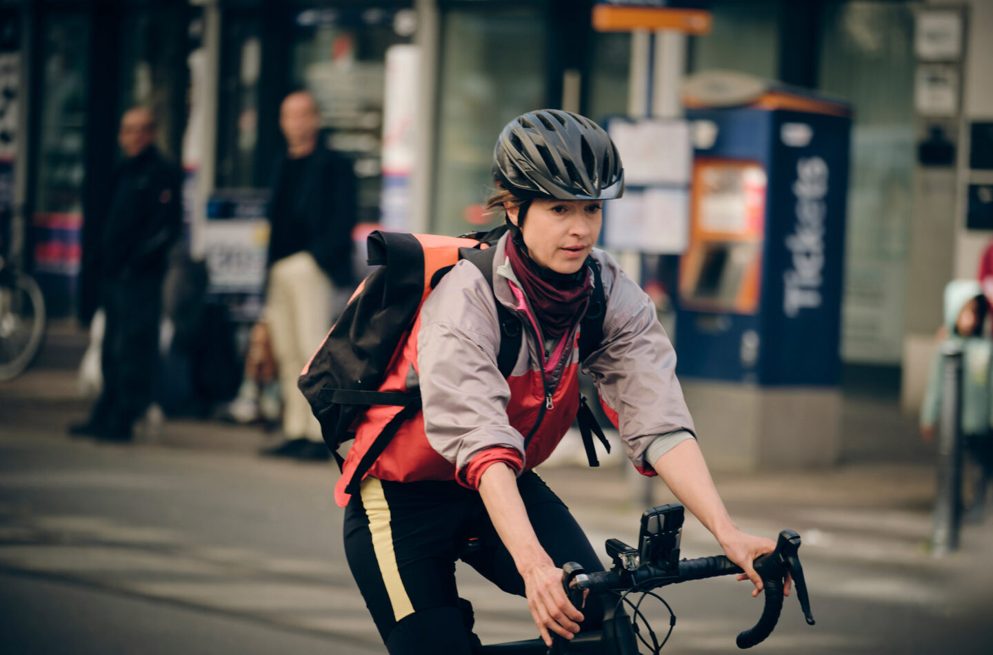 Frau auf dem Fahrrad in sportlicher Kleidung mit Helm und Rucksack.