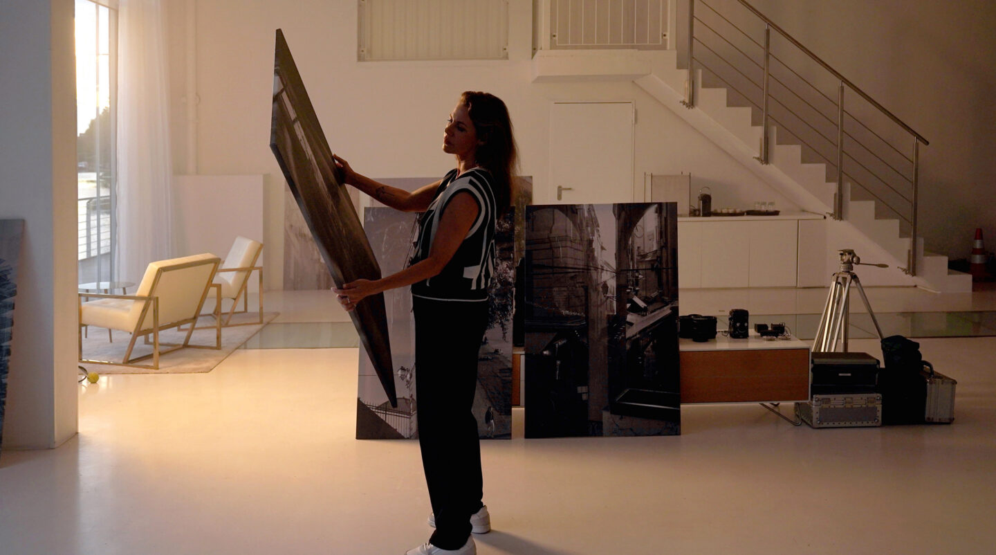 Frau hält ein großes Bild in einem modernen Raum.