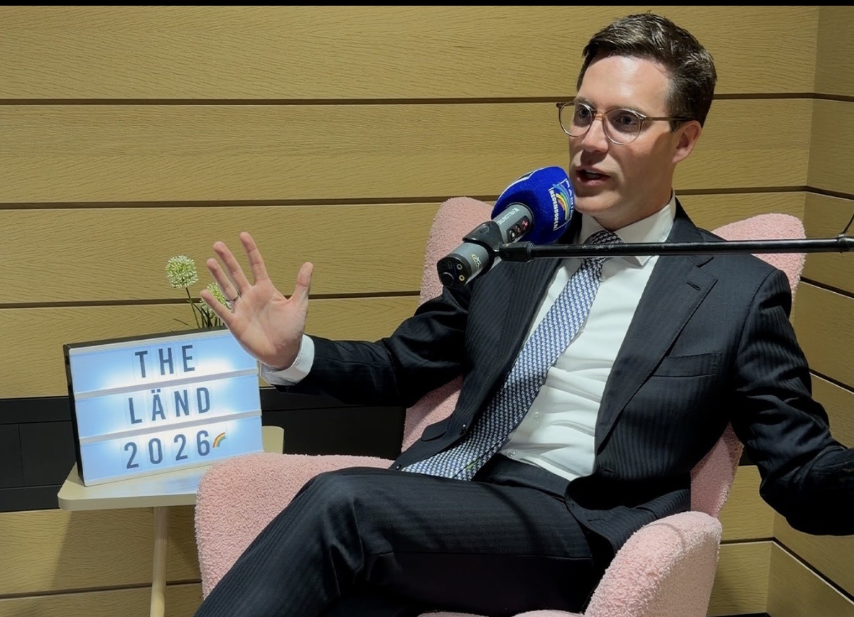 Mann im Anzug spricht in einem Podcast-Setting mit Mikrofon.