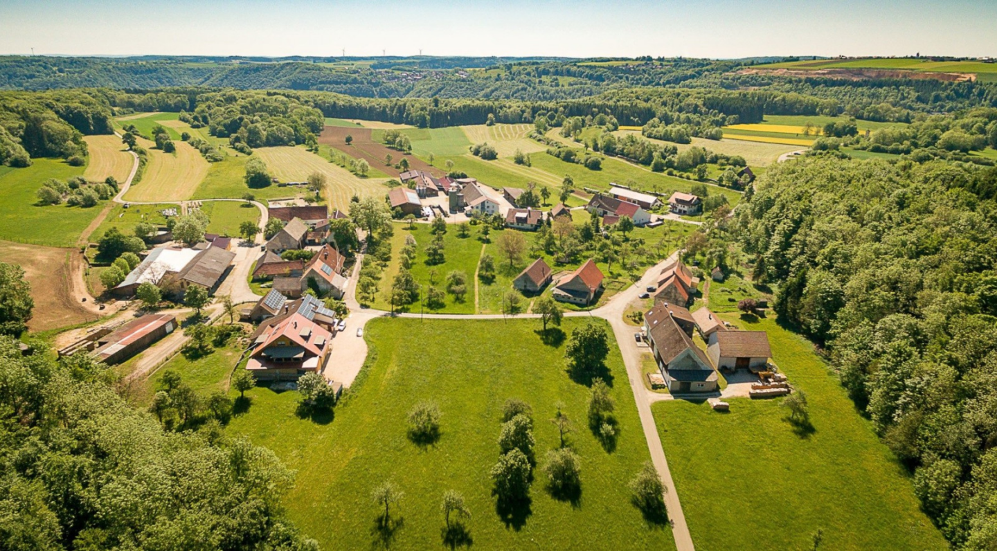 Luftaufnahme eines ländlichen Dorfes mit grünen Wiesen und Häusern.