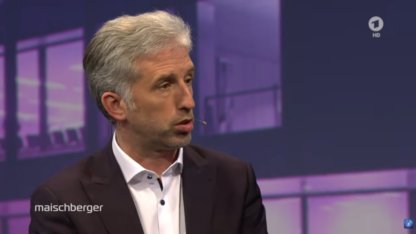 Mann mit grauen Haaren spricht in einer Talkshow.