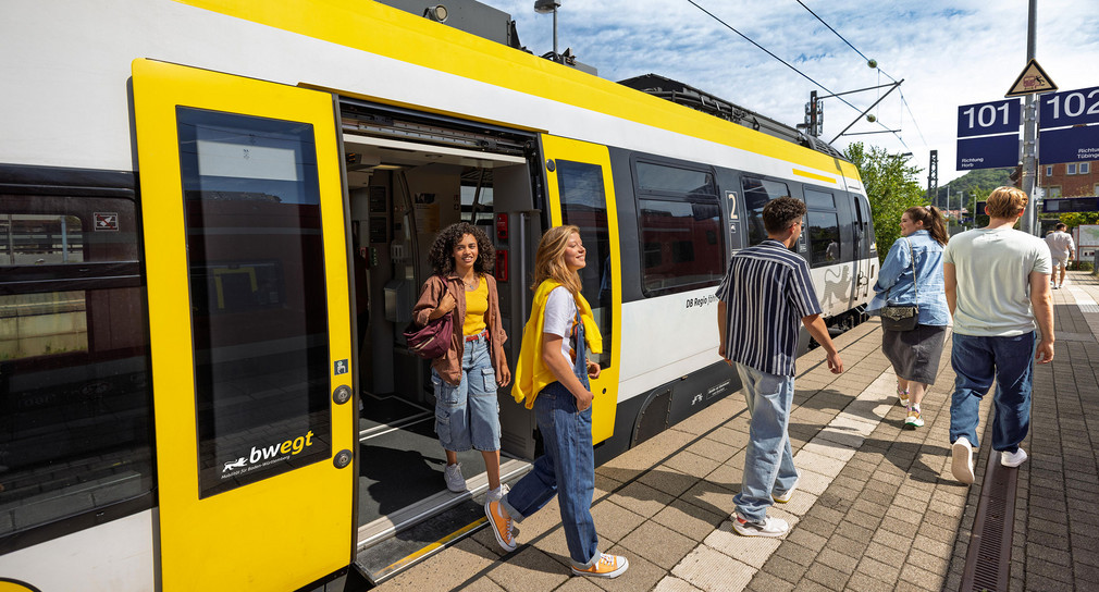 Reisende steigen an einem Bahnhof in einen Zug ein