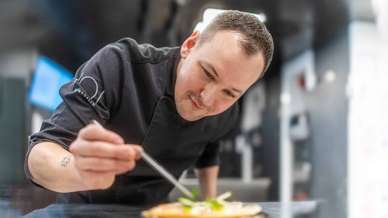 Alexander Mayer, neuer Head Chef des Eatrenalin, konzentriert sich in einer modernen Restaurantküche darauf, ein Gericht mit Präzision anzurichten.