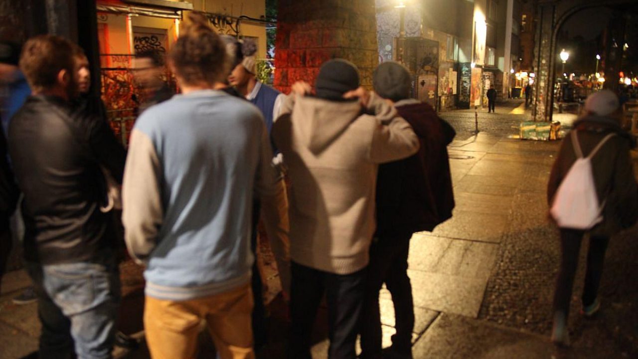Gruppe von Menschen in einer urbanen Umgebung bei Nacht.