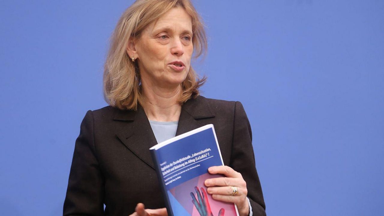 Frau spricht und hält ein Dokument in der Hand vor blauem Hintergrund.