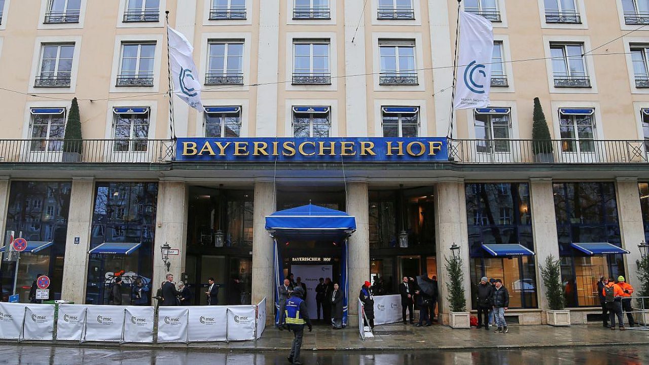 Eingang zum Hotel Bayerischer Hof mit Menschen und Fahnen.