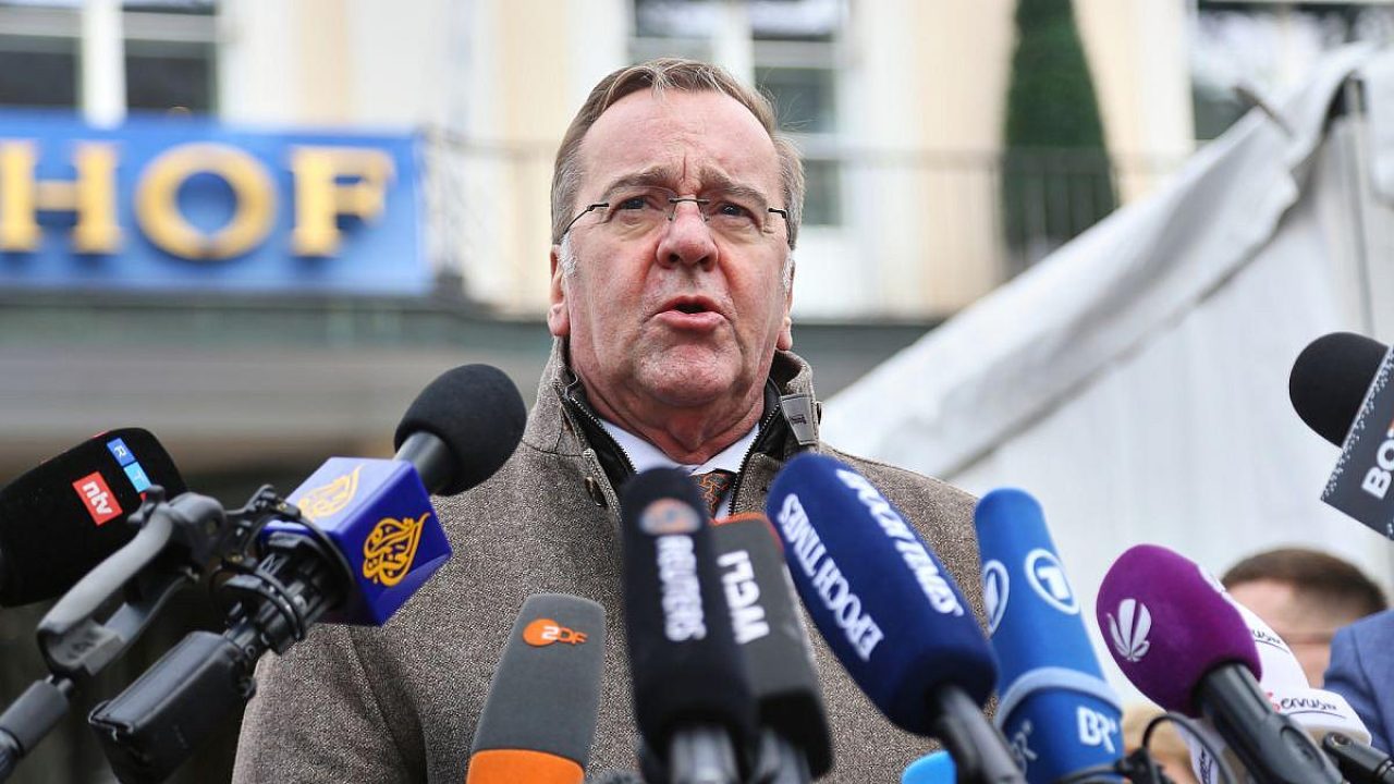 Mann spricht vor Mikrofonen in einem öffentlichen Raum.