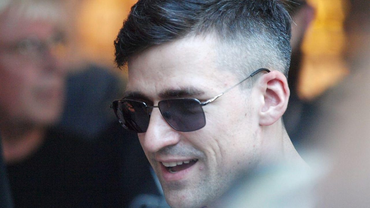 Mann mit Sonnenbrille lächelt in einer Menschenmenge.