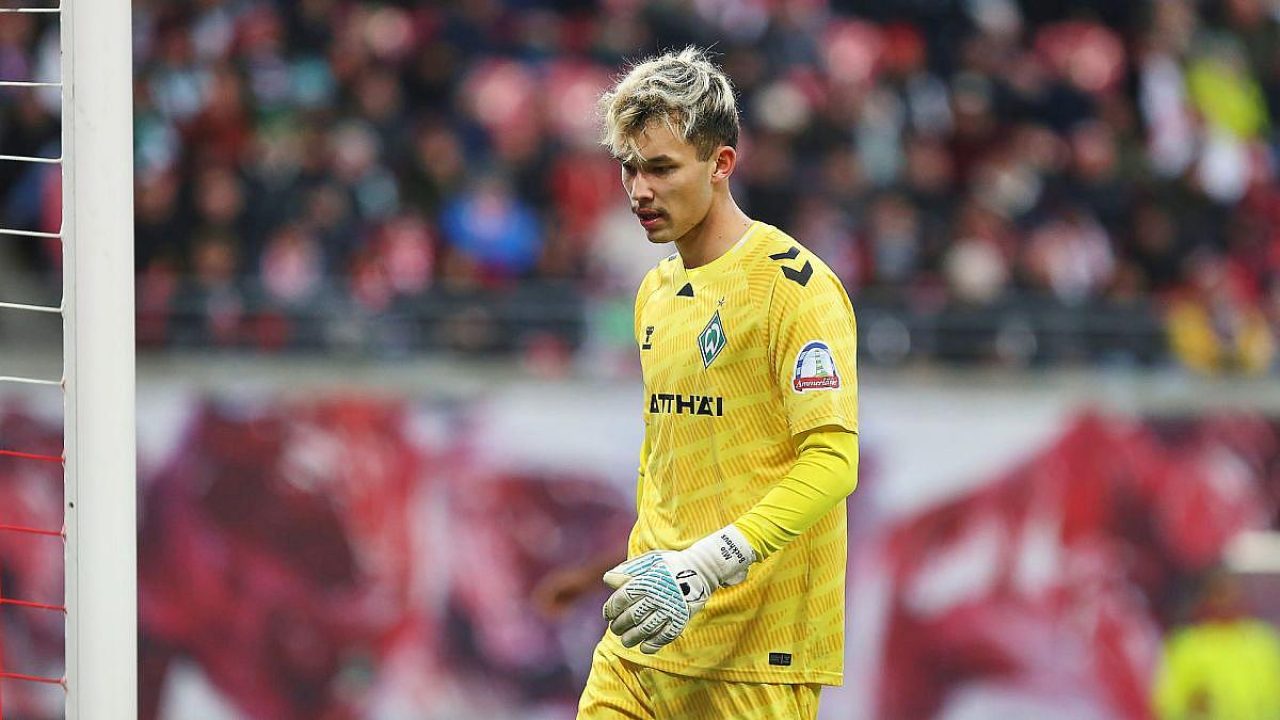 Junger Torwart in gelber Ausrüstung mit Handschuhen, nachdenklich auf dem Spielfeld.