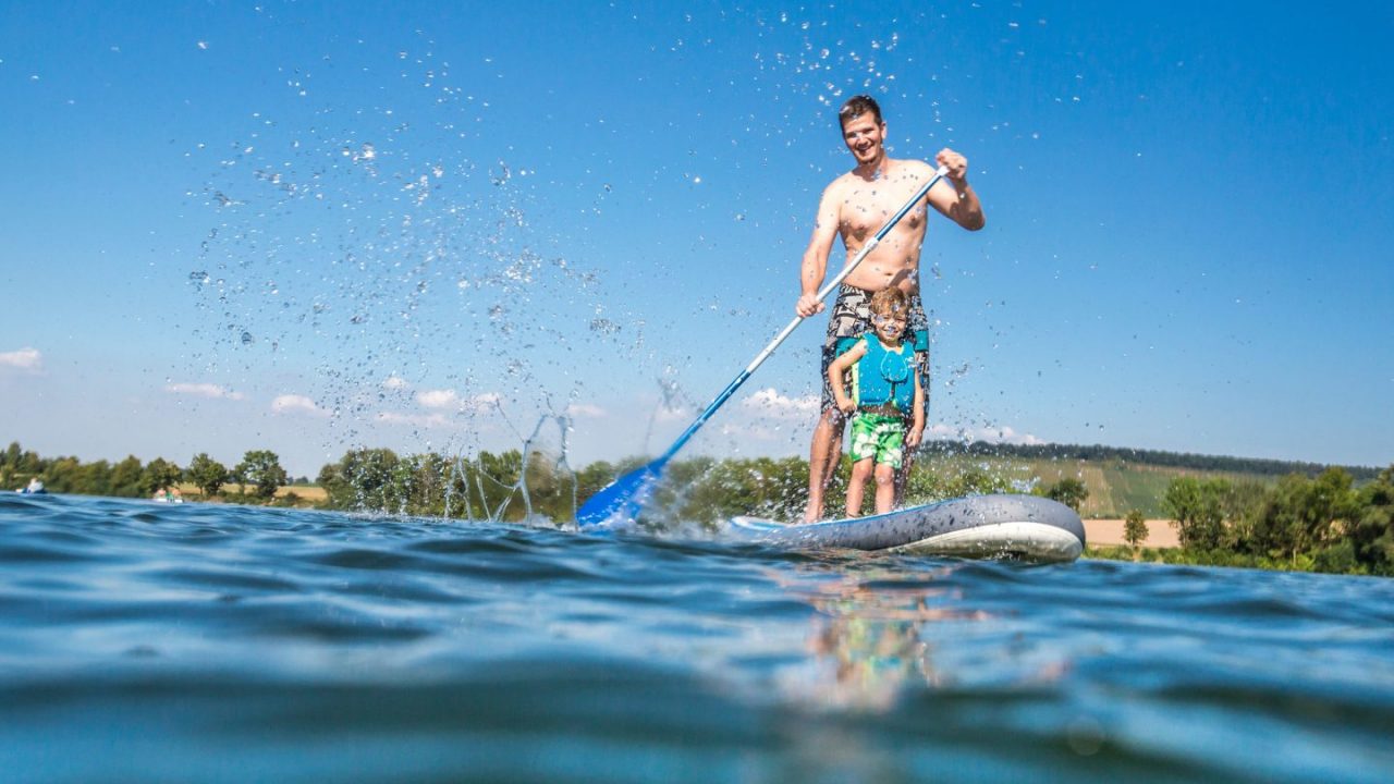 Vater und Sohn haben Spaß beim Standup-paddling auf dem See